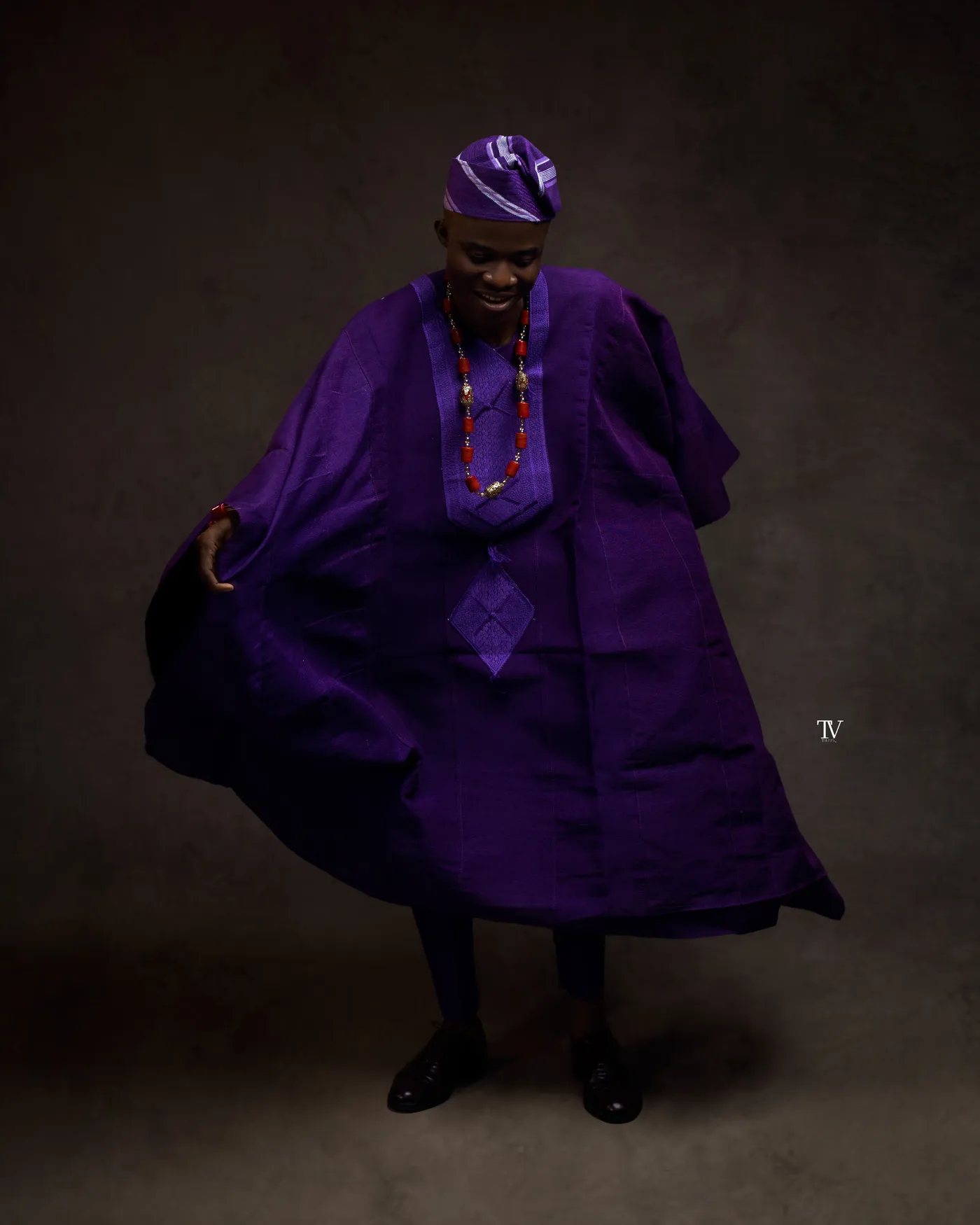 Opeyemi Daniel photographed in a purple agbada against a dark studio backdrop.