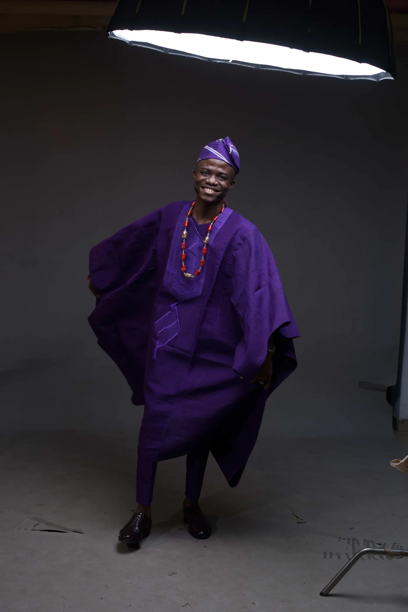 Opeyemi Daniel in a purple agbada on a studio set